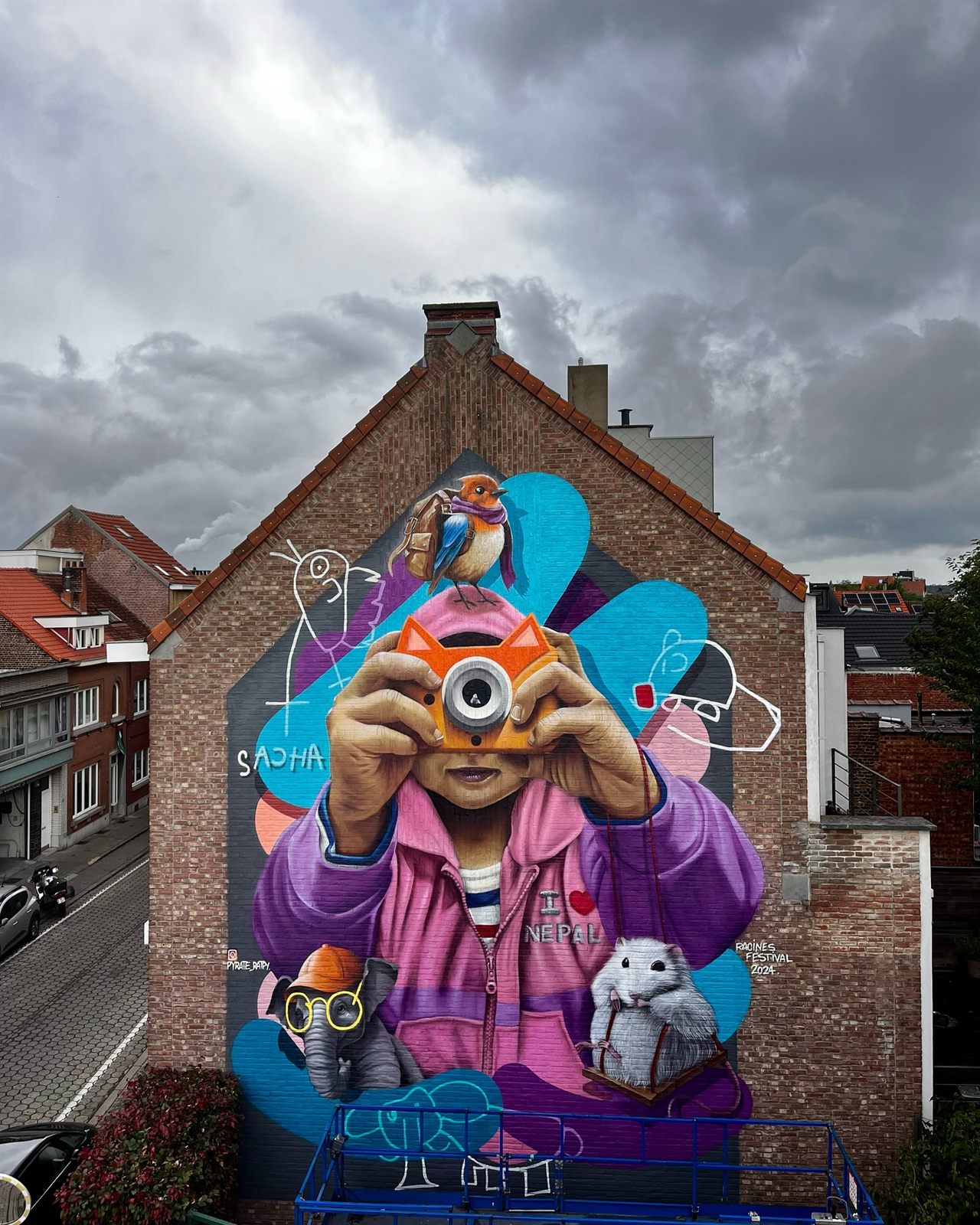 Fresque d'un enfant photographiant la rue, surmonté d'un oiseau