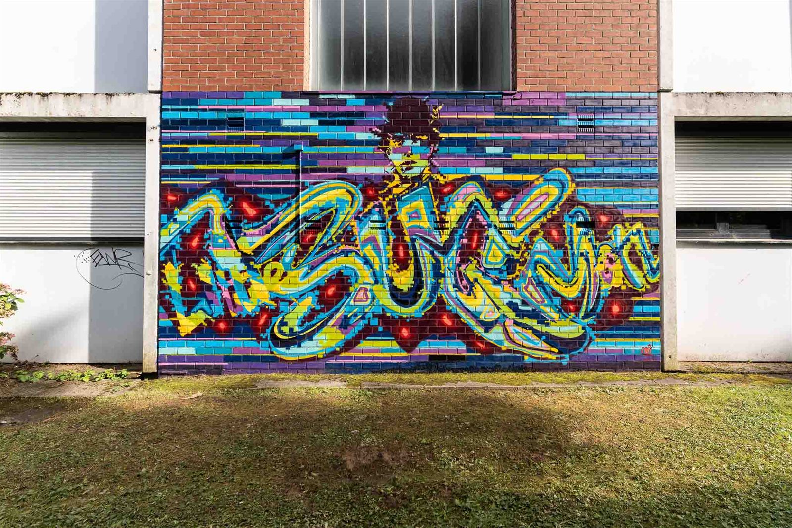 Fresque de lettrage graffiti bleu et jaune sur mur de briques