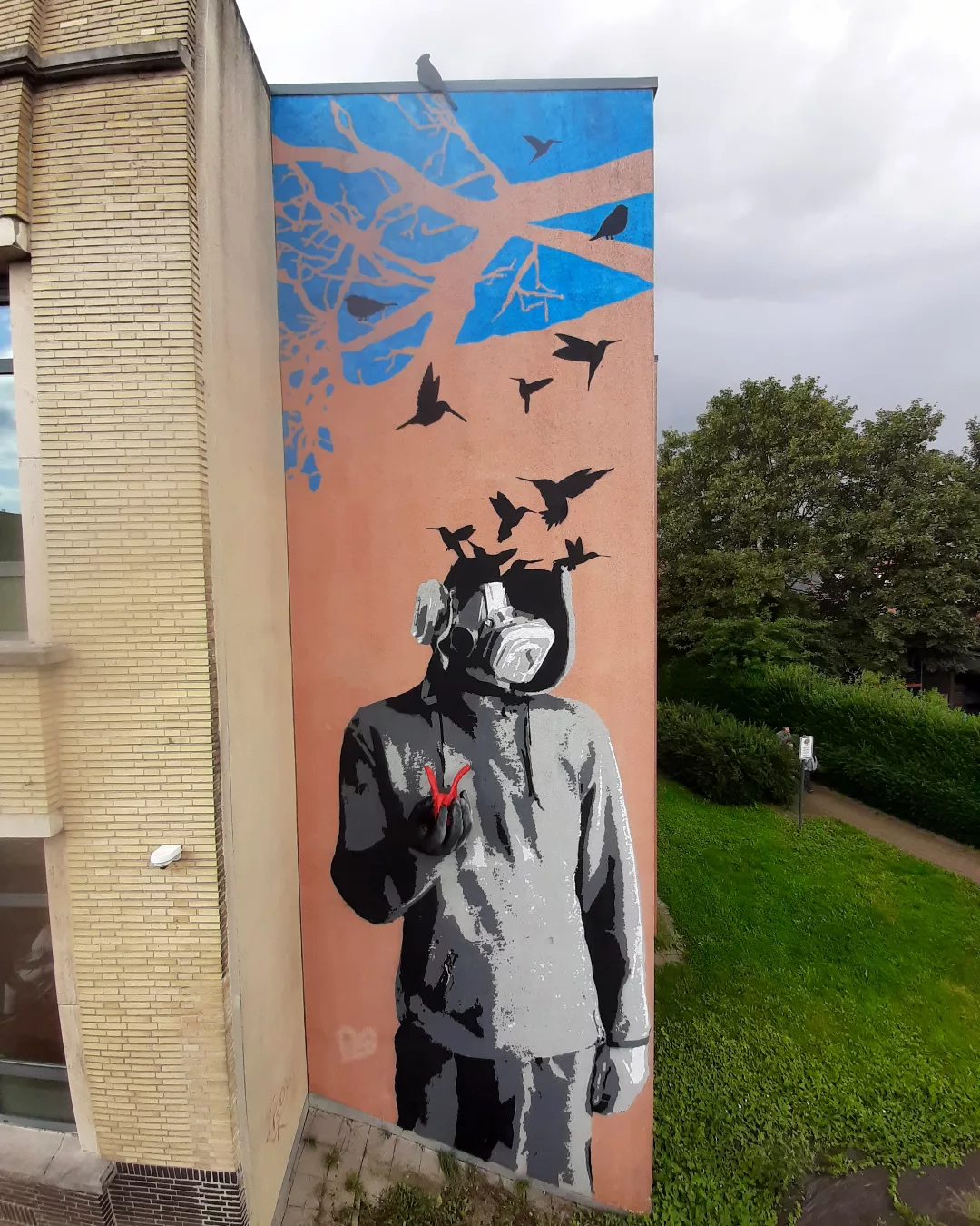 Fresque d’une silhouette au masque à gaz d’où s’envolent des oiseaux